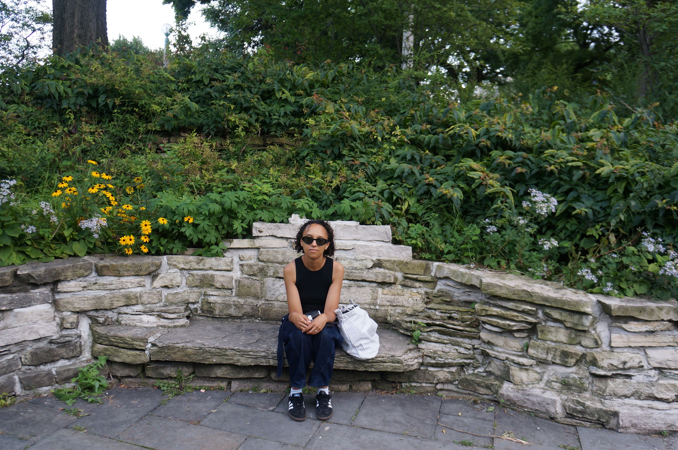 Katana Smith, a woman sitting on a bench surrounded by green brushes.