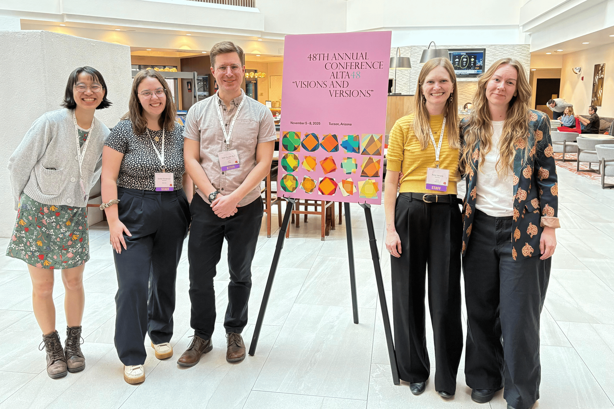 On-site ALTA staff members smile around a poster for the 48th annual ALTA conference.