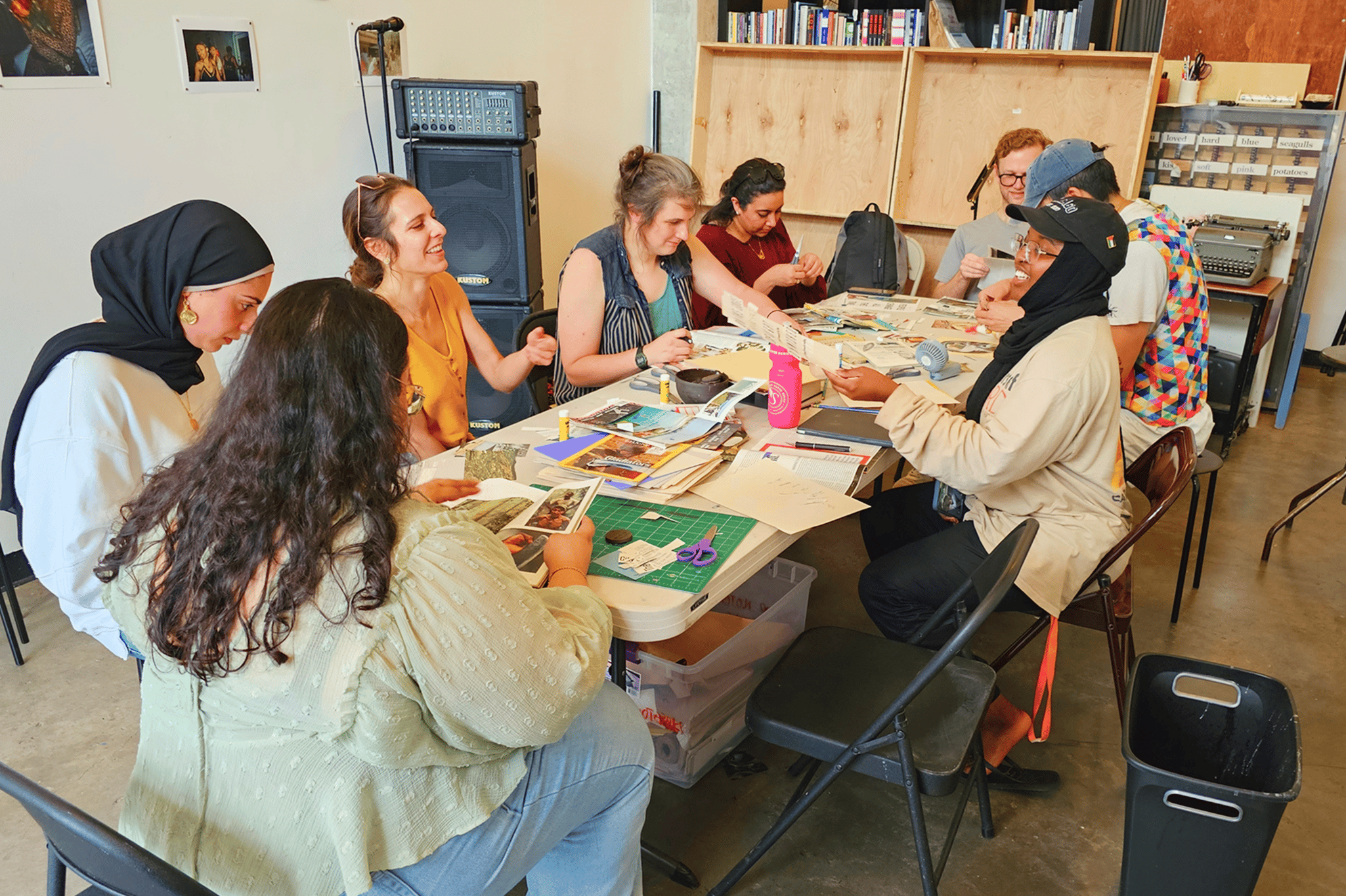 Adults at a table full of colorful paper, glue, and other materials for making collages.