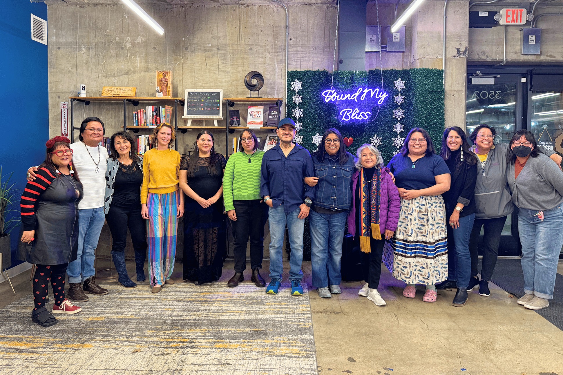Group of adults smiling in front of a sign that says "Found My Bliss"