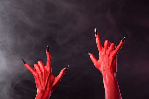 Satanic looking hands giving the heavy metal devil horns sign.