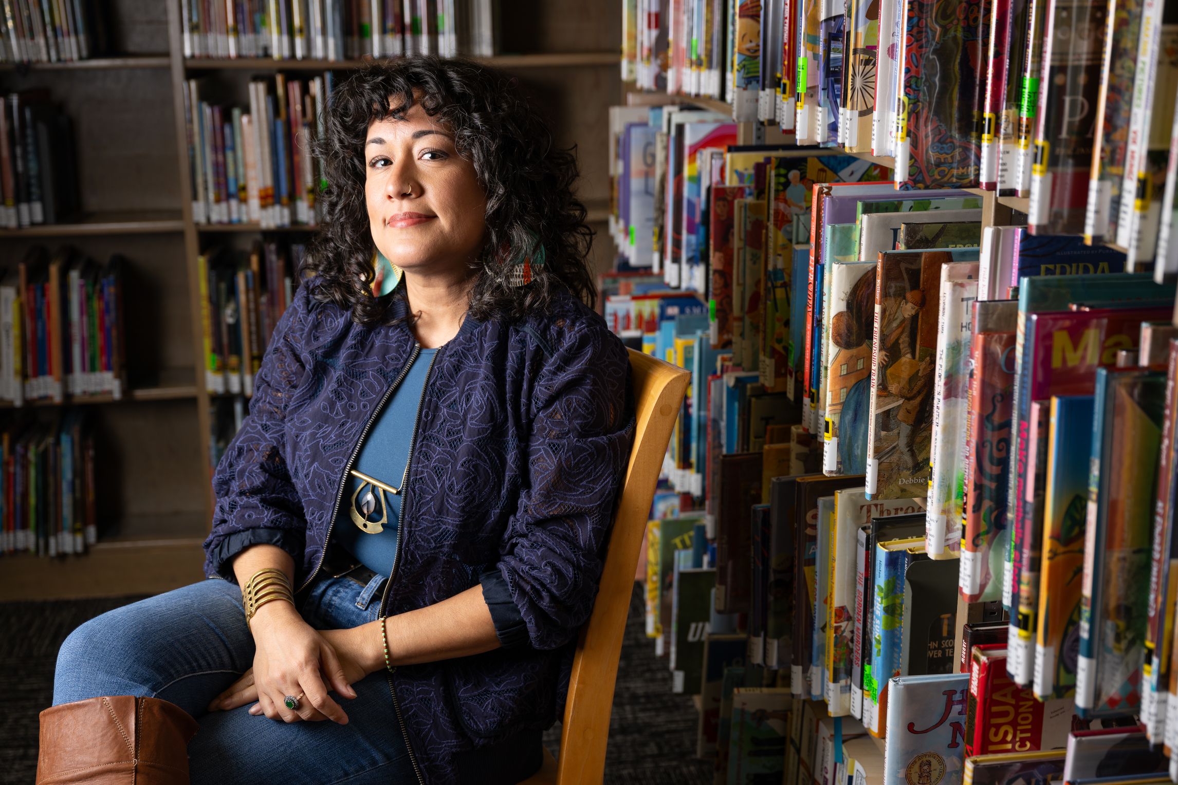 Mayda Alexandra del Valle sjtting in a room full of books