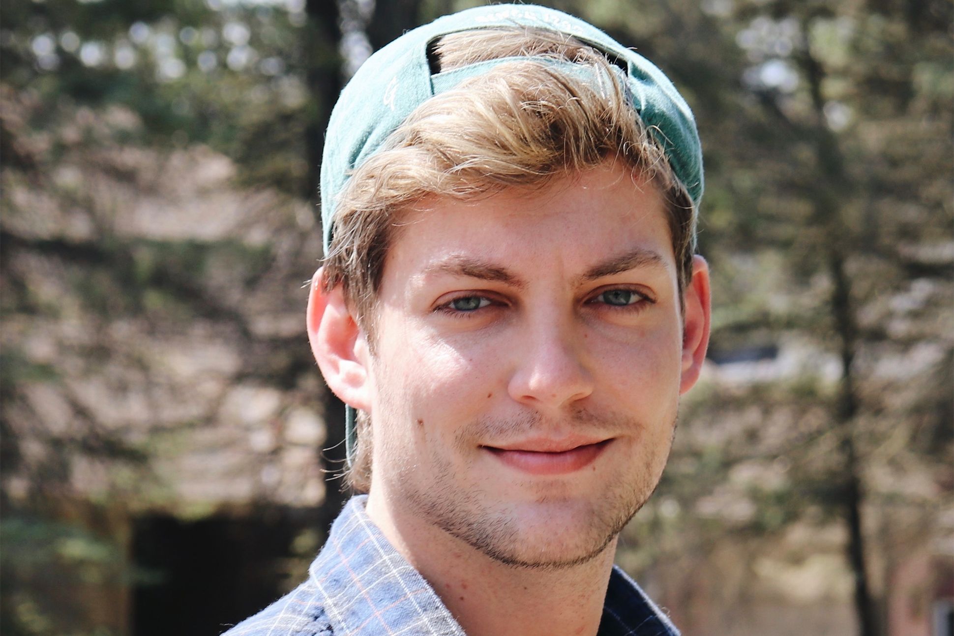A photograph of Max McDonough outside, wearing a backwards baseball cap.