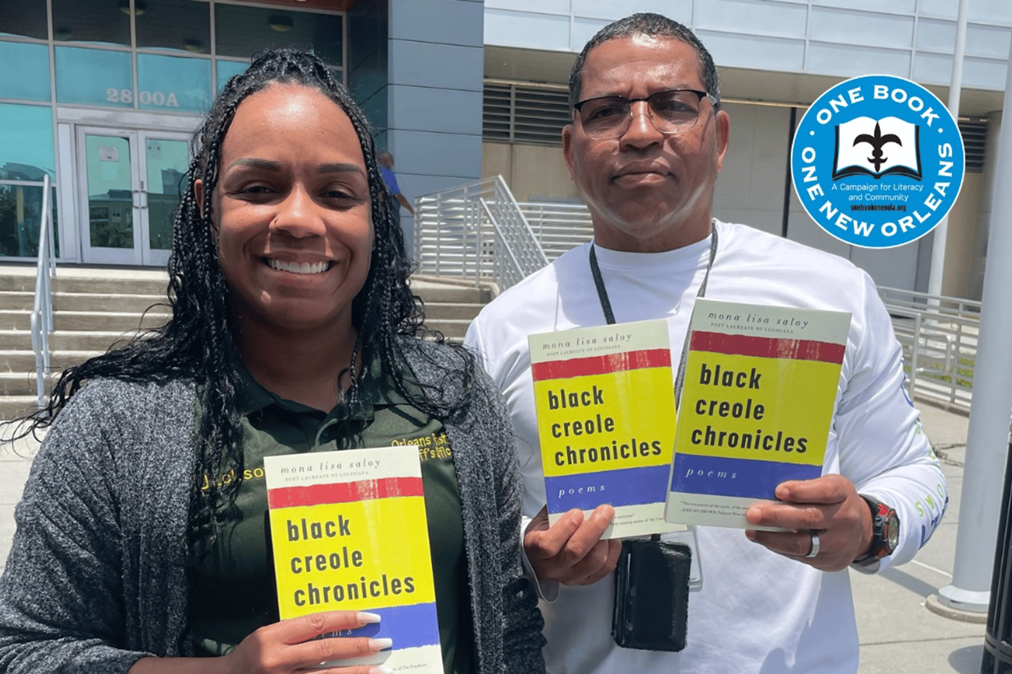 Two adults holding books with the title Black Creole Chronicles