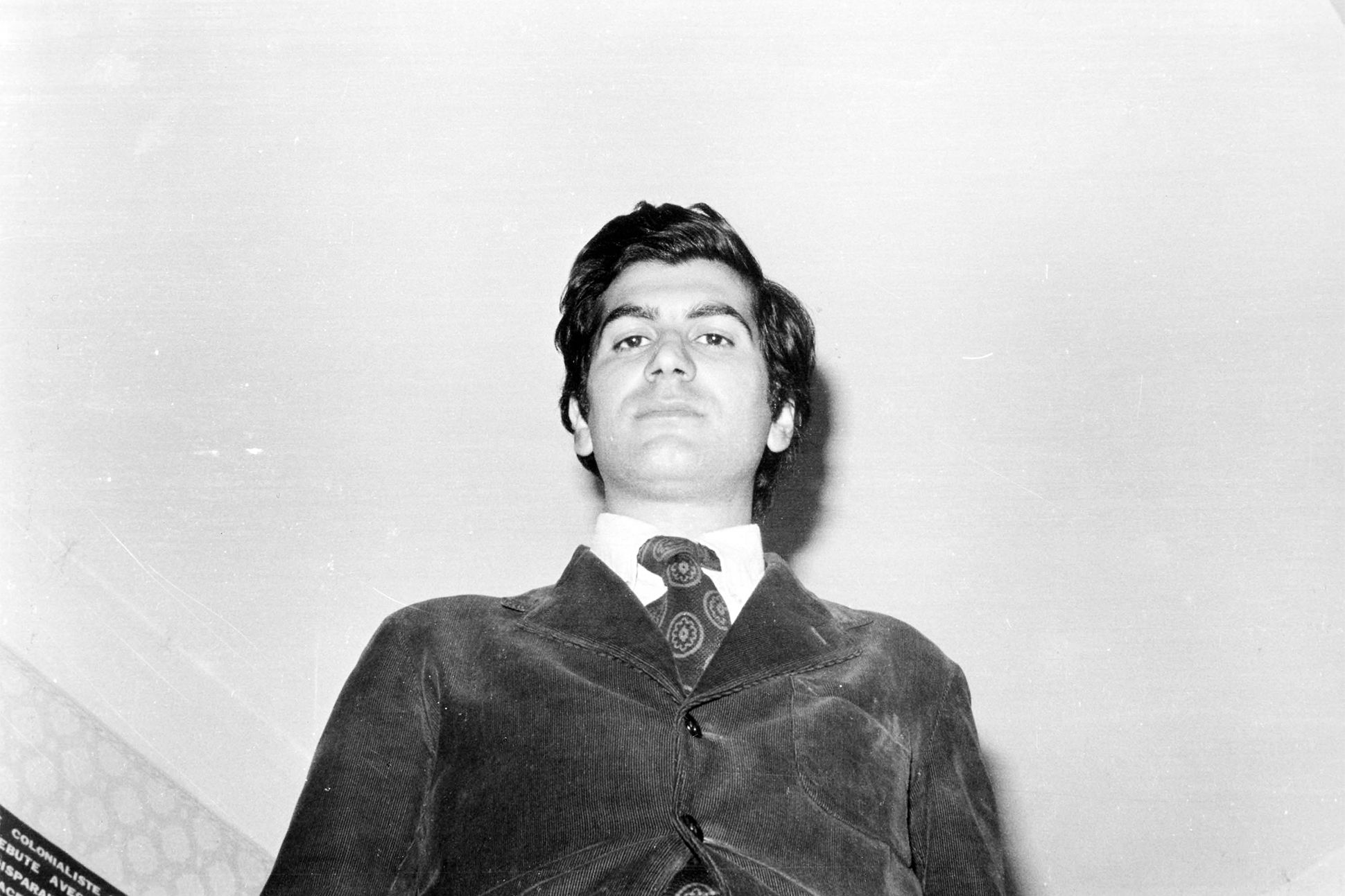 A black-and-white photograph of Dario Bellezza looking down into the camera.