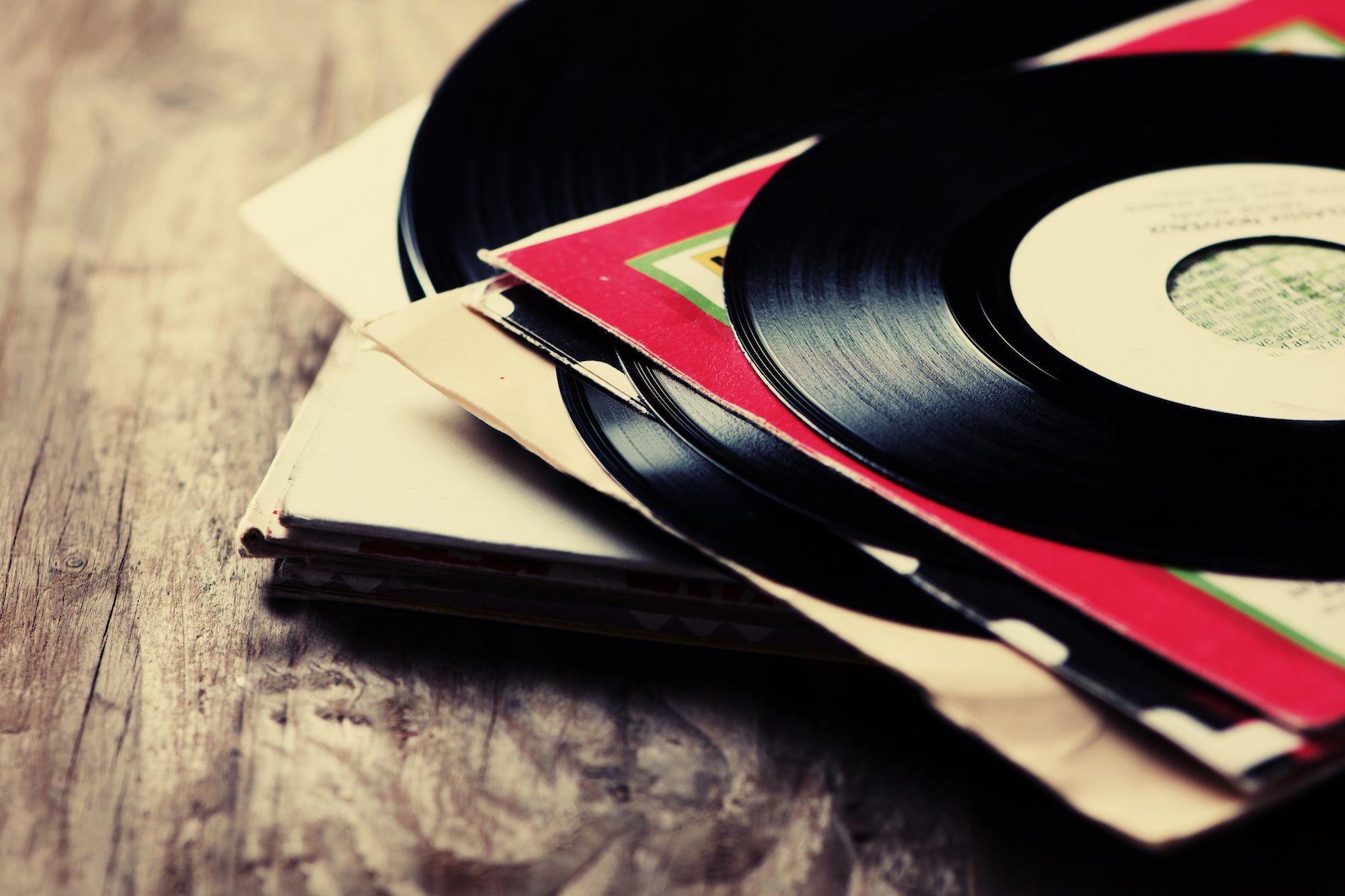 Pile of old vinyl records on a wooden table.