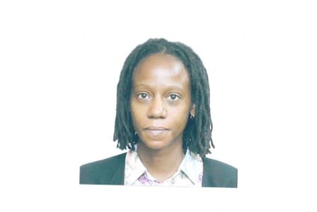Passport photo of a African American woman with short braided hair in a suit with pink shirt