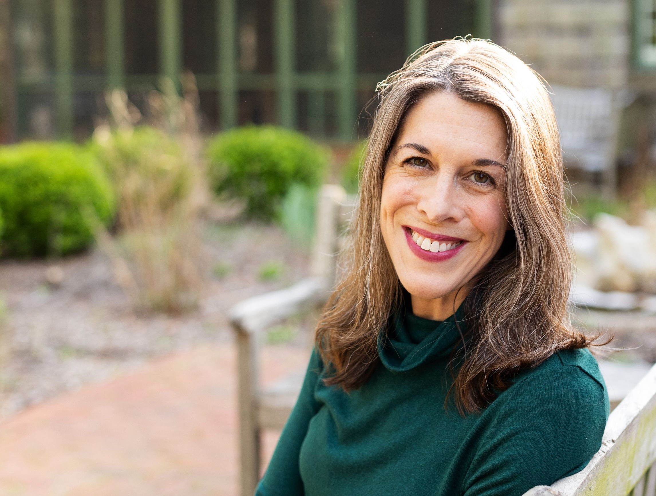 Catherine Pierce, a white female sitting and smiling on a bench outside a museum.