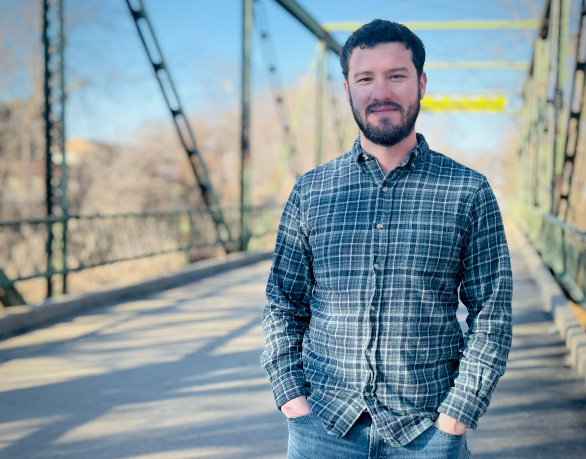 Caleb Braun, a white male in plaid shirt standing on a bridge.