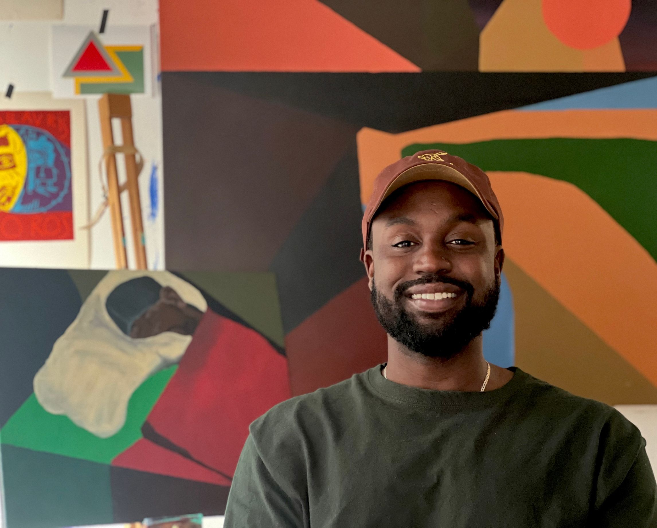 Artist Jermaine Nolen seated in his studio in front of a collection of his original work.