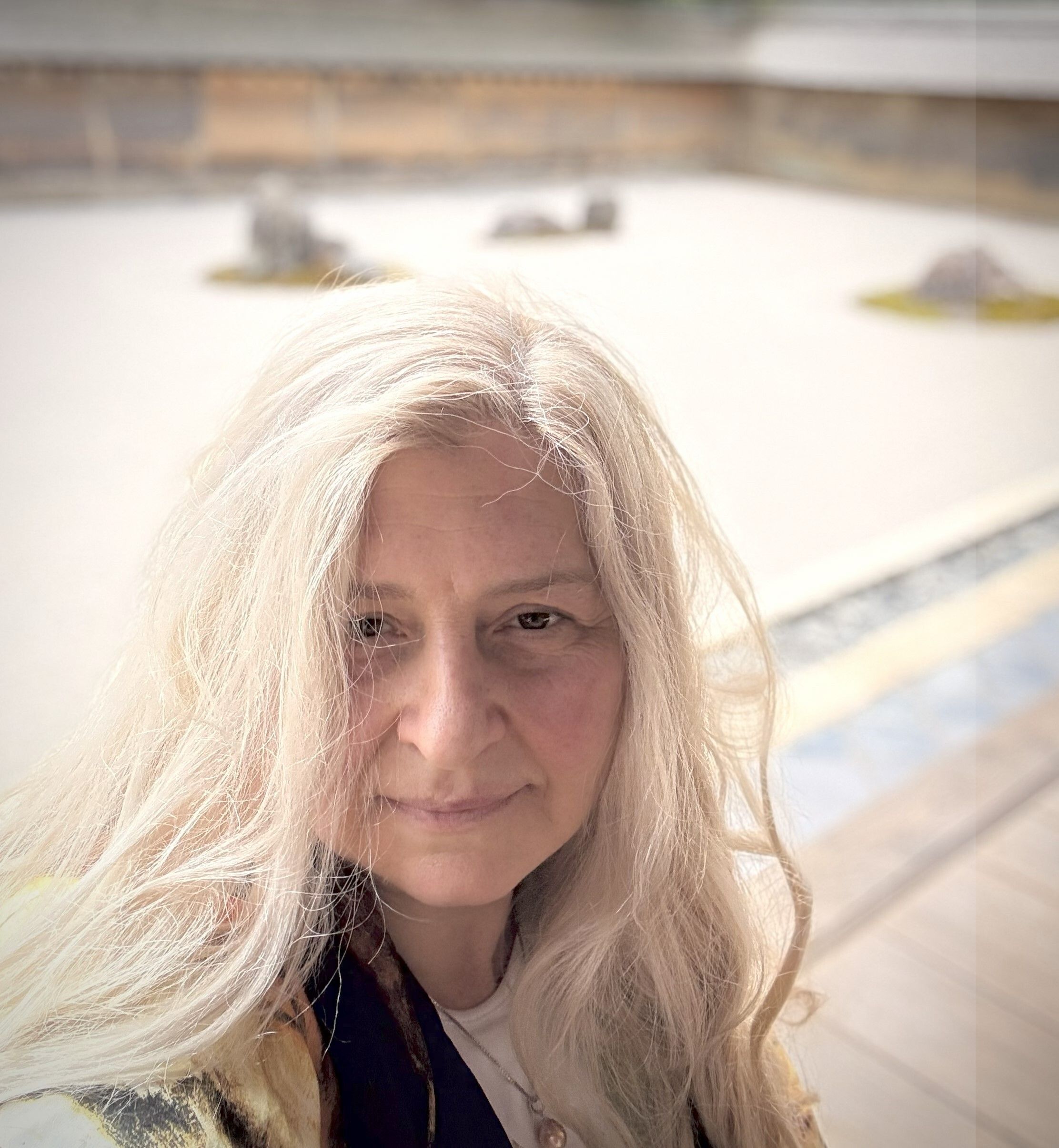 Olga Maslova, a white woman with long blond hair stand in front of Kyoto Zen garden