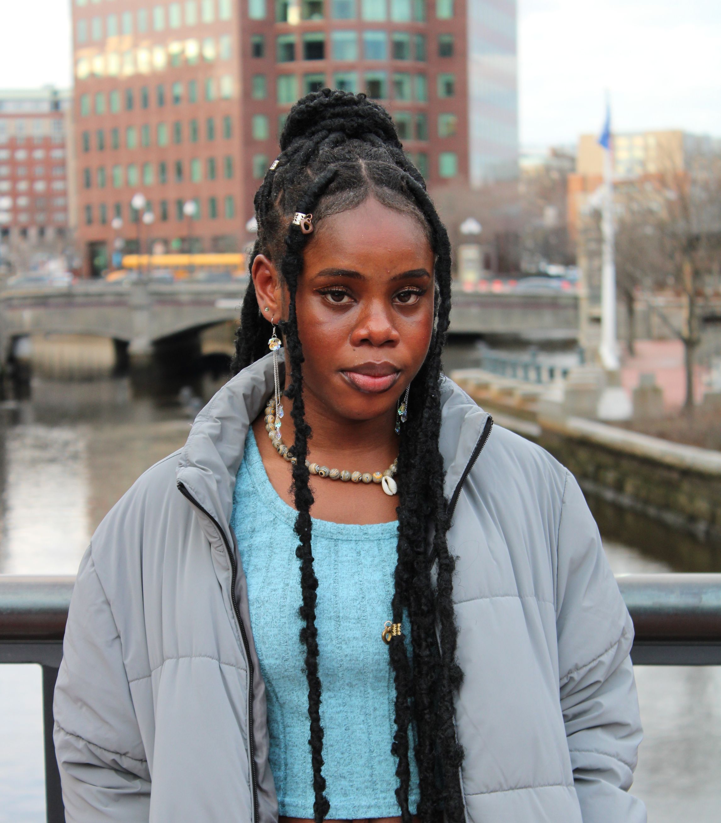 Maryhilda Ibe, Black woman with locs in a high ponytail, wearing a grey puffer jacket.
