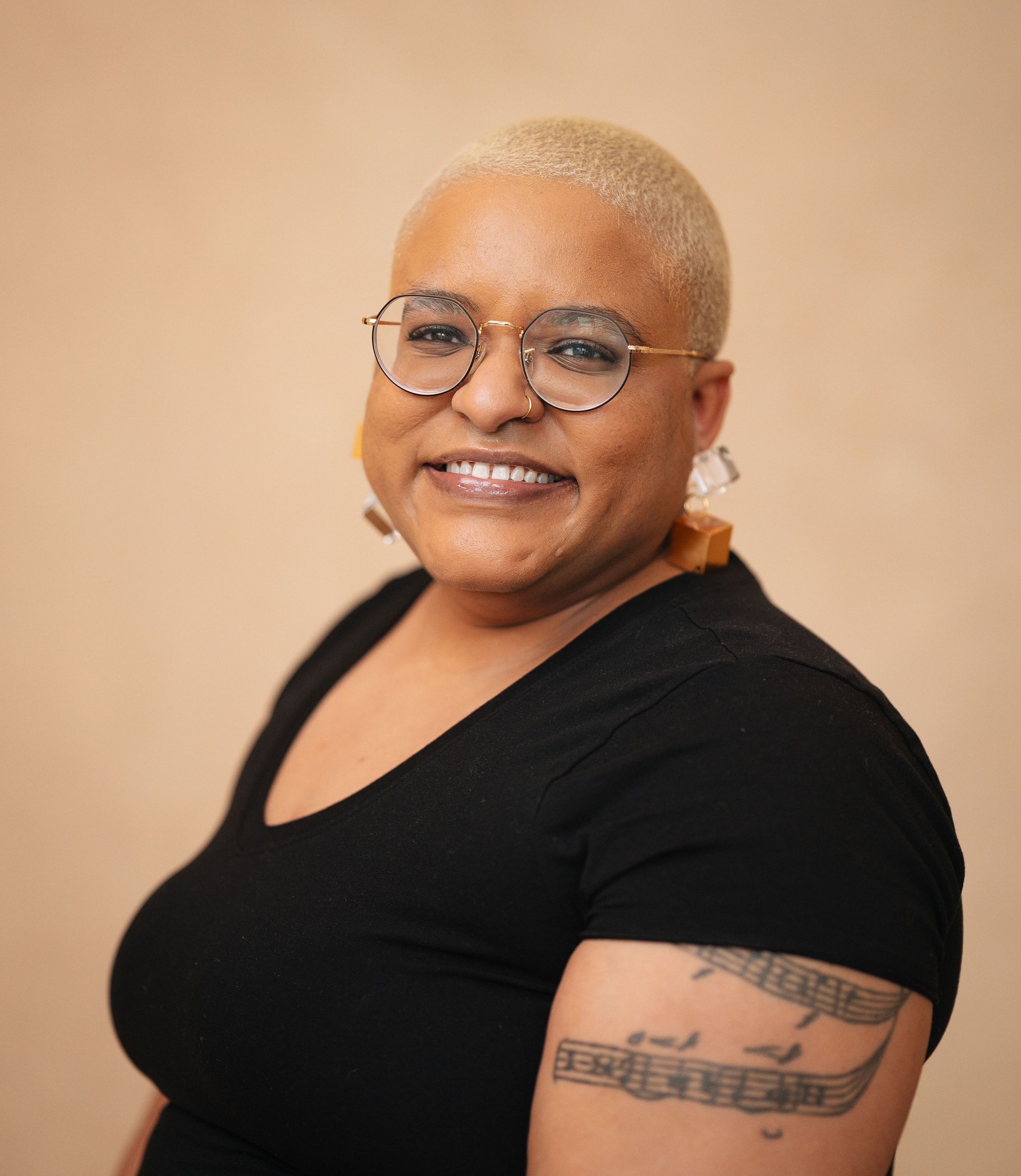Sena Dawes, a Black woman with short hair, stands in front of a beige background
