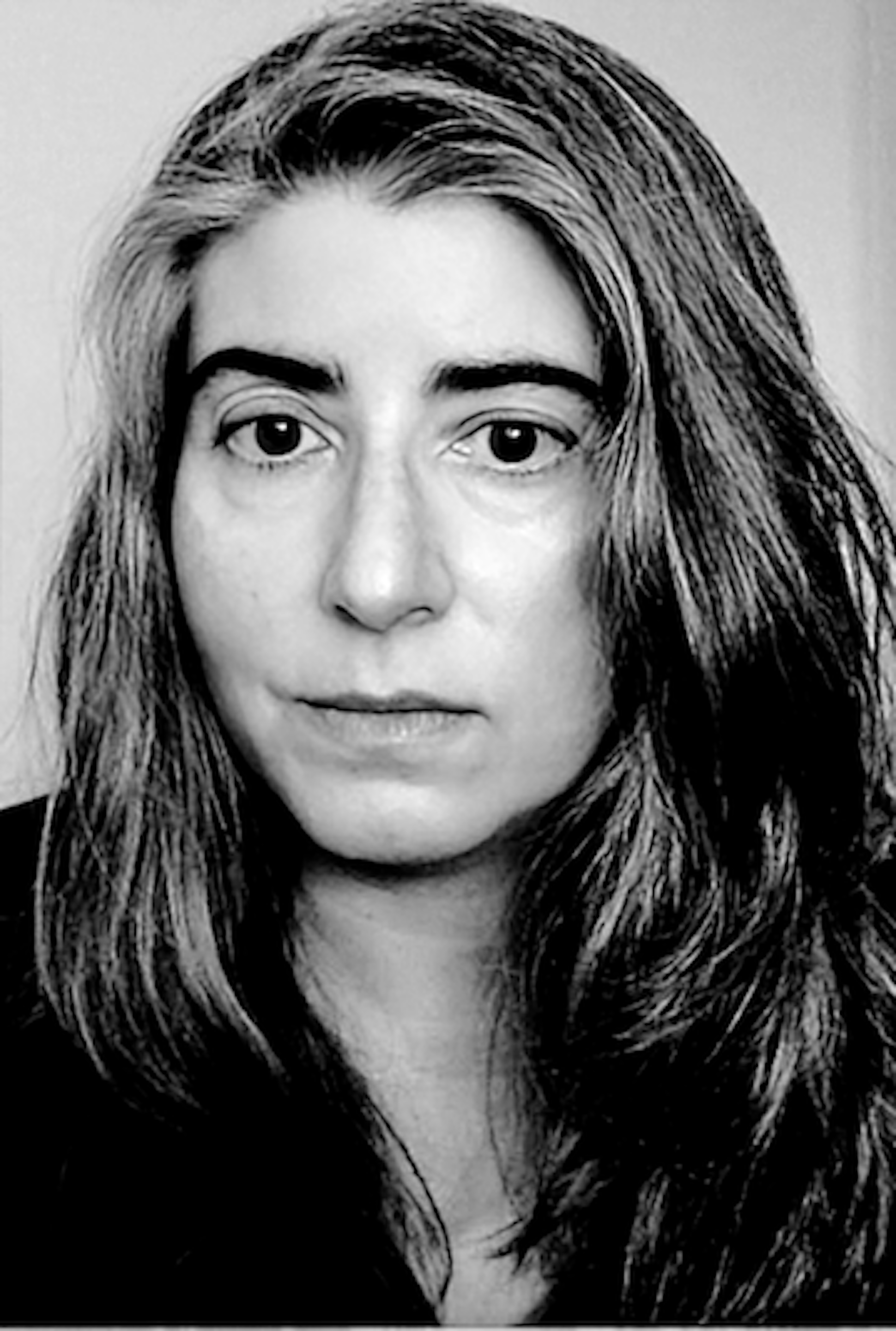Black-and-white headshot of Eleni Stecopoulos, a woman with long dark and silver hair and large dark eyes looking slightly away from the camera, with a slight, closed smile.