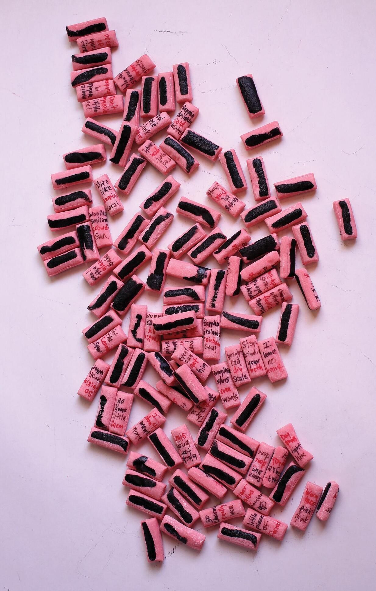 Photograph of Super Bubble chewing gum with four words written  in varying colors on one side of each piece and black marker on the other side